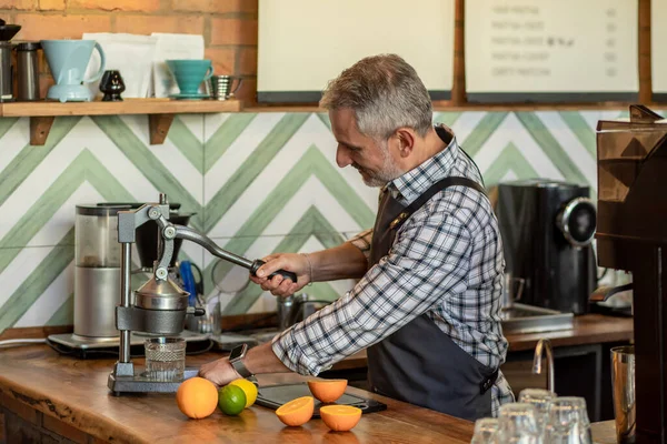 Making juice. Man in plaid shirt standing near juicer and making juice