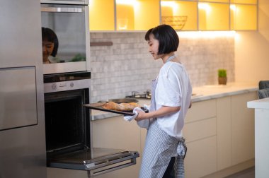 Baking pasrty. Young housewife baking something in the oven and looking busy