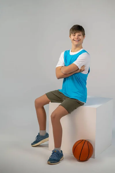 Feeling good. A contented boy sitting on a cube and smiling