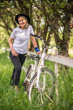 Having fun. A woman in black hat and with a bike looking enjoyed and entertained