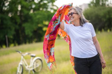 Harmony. A woman with a bright scarf in the meadow feeling peaceful and enjoyed