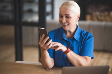 Making a call. A smiling good-looking woman with a phone in hands