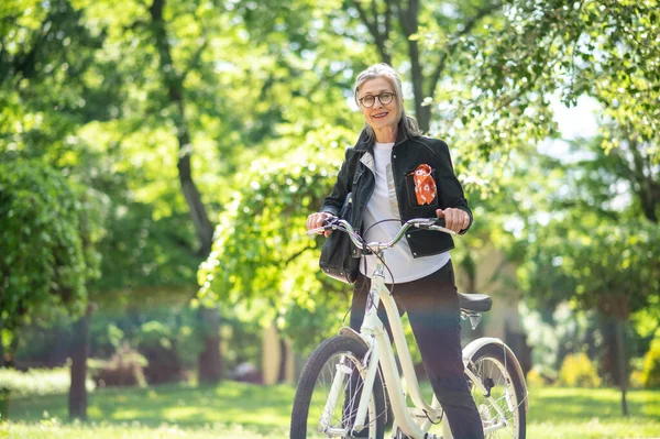 On a bike. Mature woman on a bike in a summer park