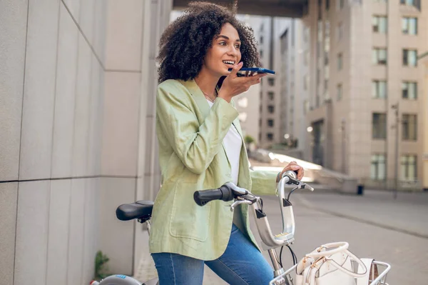 Voice message. A curly-haired girl recording an audio message