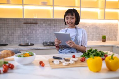 Looking for recipe. A girl in the kitchen reading a cookery blog online