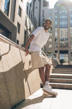 Urban style. Young guy in light clothes outside in the business area