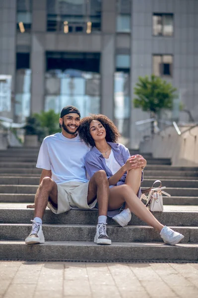 Happy couple. Young cute couple sitting on the steps and looking peaceful and happy