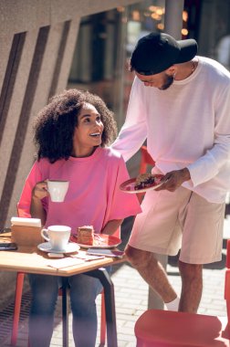 Coffee tpogether. Happy couple having coffee in the street cafe and looking enjoyed