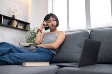 Studying. A girl sitting on the sofa with a laptop and looking busy