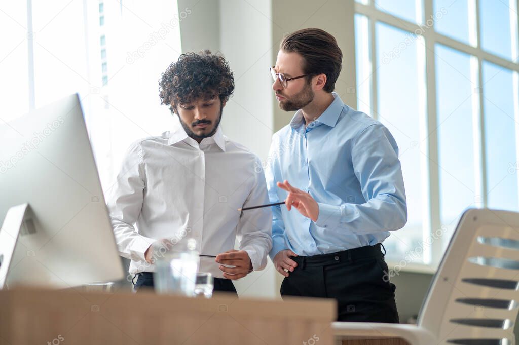 Work on project. Two businessmen looking busy while discussing project in the office