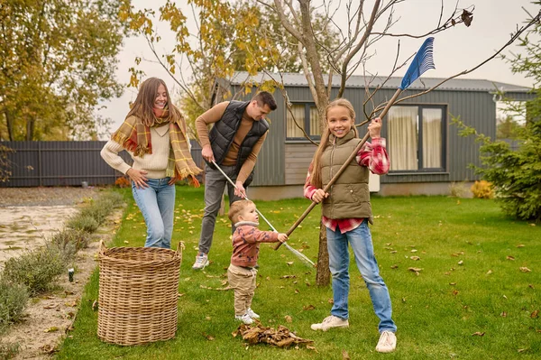 Веселая Девочка Подросток Младший Брат Помогают Родителям Сгребать Опавшие Листья — стоковое фото