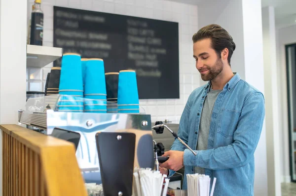 Making coffee. Barista making coffee in the cafe and looking contented