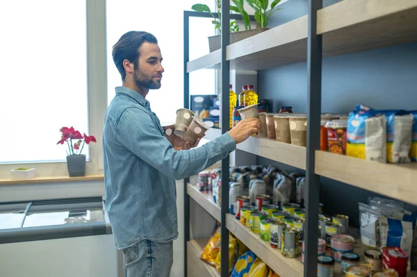 New products. Shop owner putting products on the selves and looking involved