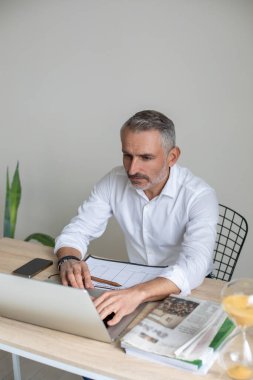 Çalışma süreci. CEO 'su çalıştığı yerde oturuyor ve dizüstü bilgisayarı üzerinde çalışıyor.