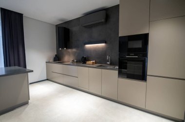 Modern çift katlı duvar fırını ve dolapları olan şık bir tek duvarlı mutfak.