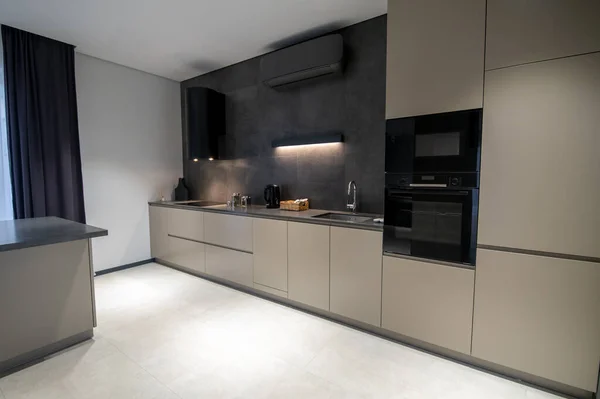 Interior of a stylish one-wall kitchen with the modern built-in double wall oven and cabinets