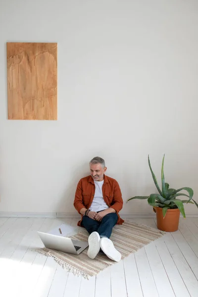 Working on project. A bearded man in terracotta shirt working on the project and looking involved