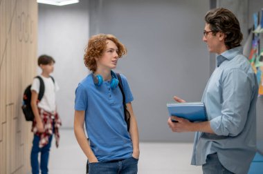 Okul çocuğu teneffüste sınıf arkadaşı onu beklerken öğretmeniyle sohbet ediyor.