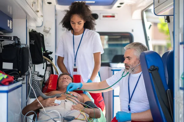 Médico Ambulancia Experimentado Auscultando Paciente Masculino Durante Cardiograma Asistido Por — Foto de Stock