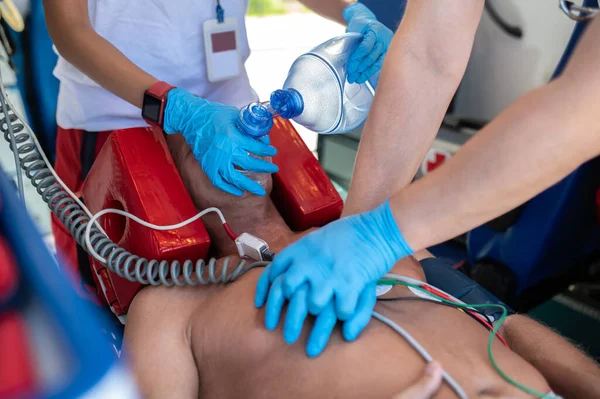 Paramedic putting the oxygen mask on the critical patient while the colleague doing chest compressions
