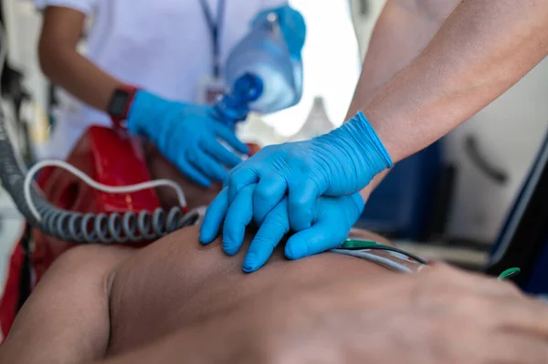 Cropped photo of the team of paramedics in sterile gloves carrying out CPR on a critical patient