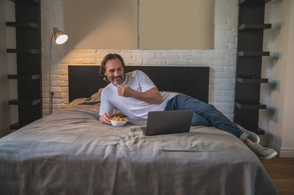Odpočívá Muž Odpočinku Práci Jíst Občerstvení Při Sledování Něco Online — Stock fotografie