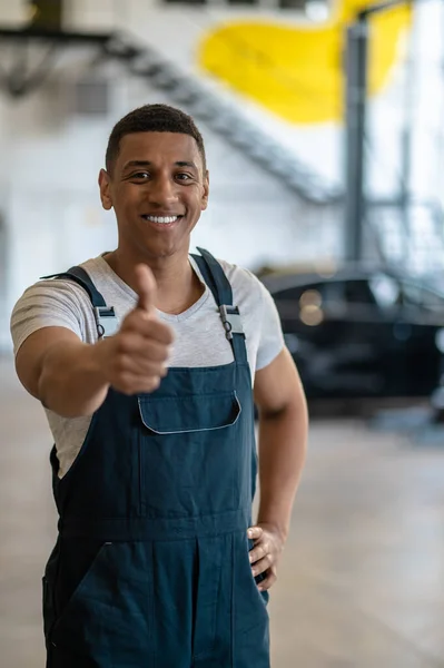 Sonriente Joven Trabajador Taller Automóviles Haciendo Cartel Pulgares Hacia Arriba —  Fotos de Stock