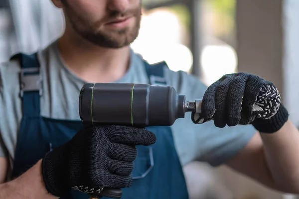 Cropped photo of a workman in work gloves attaching the nozzle to an impact wrench