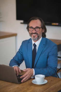 Yoğun bir gün. Gözlüklü yakışıklı adam dizüstü bilgisayarla çalışıyor.