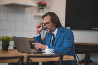 Yoğun bir gün. Gözlüklü yakışıklı adam dizüstü bilgisayarla çalışıyor.