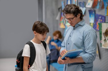 Öğrencilerle konuş. Erkek öğretmen öğrencileriyle konuşuyor ve sıkı görünüyor.