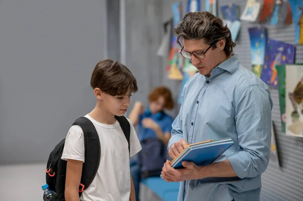 Öğrencilerle konuş. Erkek öğretmen öğrencileriyle konuşuyor ve sıkı görünüyor.