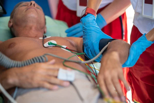 在同事的帮助下 辅助医务人员将血压袖口围在病人上臂周围 — 图库照片