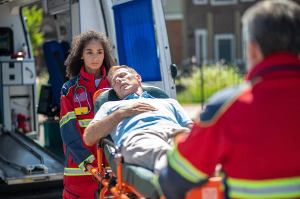 Paramedis Wanita Serius Mengi Korban Kecelakaan Mobil Pada Tandu Yang Stok Gambar