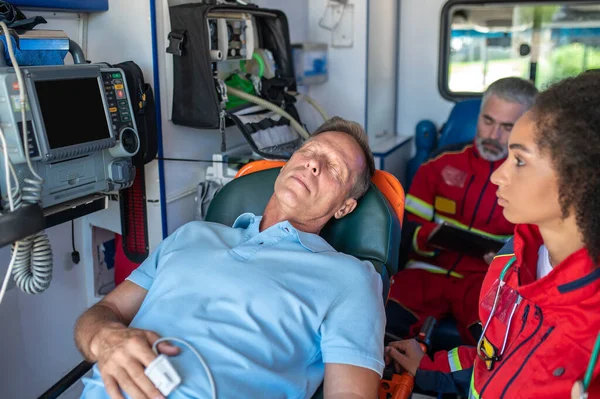 Sanitäterin Und Ihr Kollege Fahren Rettungswagen Mit Dem Bewusstlosen Männlichen Stockbild