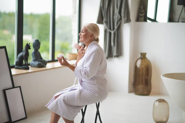 Joyous Female Sitting Stool Bathroom Window While Applying Cosmetic Cream — Stock Photo, Image