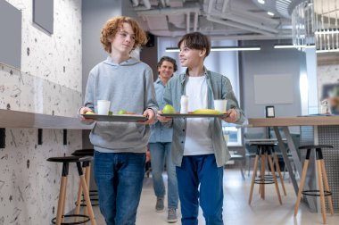 Birlikte öğle yemeği. Okul çocukları ve çaylakları okul kantininde öğle yemeği yiyorlar.