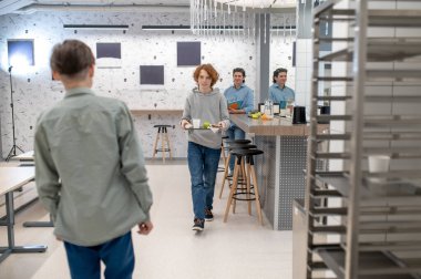 Okul kantininde. Okul çocuğu öğle yemeğinden sonra tepsisini mutfak raflarına koyuyor.