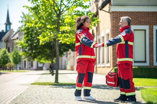 Dois Paramédicos Alegres Sorridentes Vestidos Com Uniformes Vermelhos Cumprimentando Outro — Fotografia de Stock