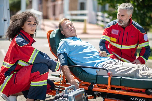 Paramedis Perempuan Membungkus Manset Tekanan Darah Sekitar Lengan Pria Sadar Stok Gambar Bebas Royalti