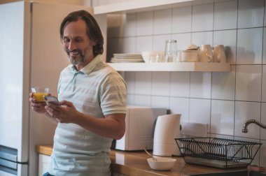 Yemek zamanı. Gülümseyen mutlu adam mutfakta kahvaltı yapıyor.