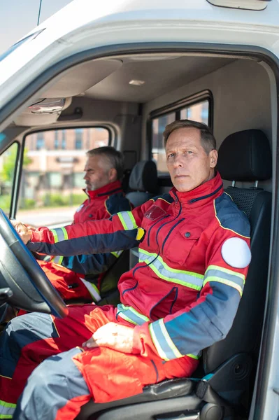 Ein Ernstzunehmender Männlicher Fahrer Und Ein Sanitäter Roten Uniformen Sitzen — Stockfoto