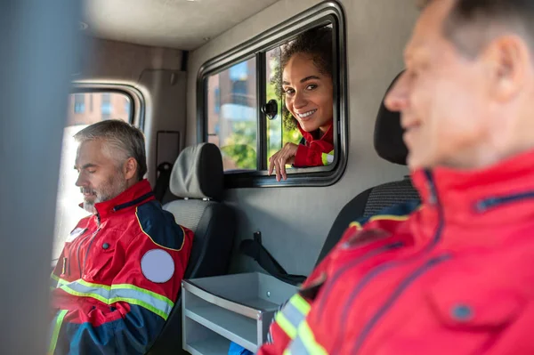 Equipo Sonrientes Complacidos Paramédicos Uniformes Rojos Sentados Juntos Vehículo Emergencia — Foto de Stock