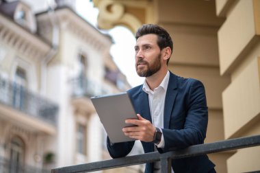 Randevudan önce. Tabletli yakışıklı, iyi giyimli bir iş adamı.