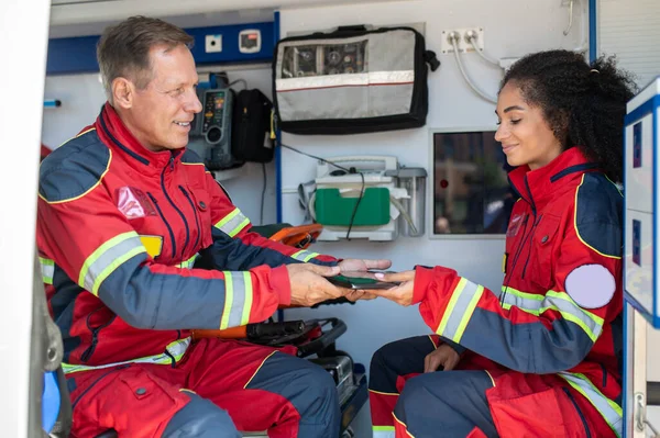 Lächelnder Arzt Überreicht Seiner Zufriedenen Kollegin Rettungswagen Den Tablet Computer — Stockfoto