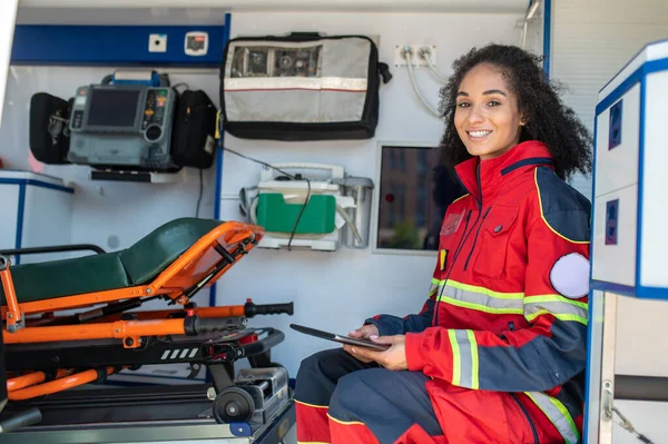 Lächelnde Rettungssanitäterin Mit Tablette Der Hand Sitzt Notarztwagen — Stockfoto