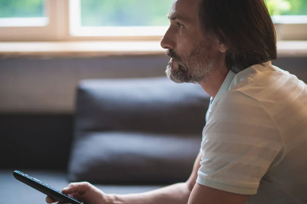 Watching tv. Man spending time at home and swithcing on tv with a tv remote