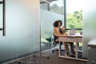 Görüntülü arama. Kıvırcık saçlı, güzel bir bayan müdürün ofiste video görüşmesi var.