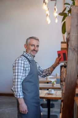 İş günü. Kafede önlüklü, sakallı, mavi gözlü bir adam.