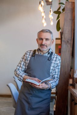 İş günü. Kafede önlüklü, sakallı, mavi gözlü bir adam.